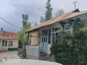 a small house with a tin roof on a street at Guesthouse Shakirbek in Arslanbob
