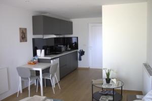 a kitchen with a small table and a kitchen with gray cabinets at Aux Boutons d'Or in Namur