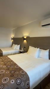 two beds in a hotel room with white pillows at Spring Water Hotel & Suites in Cuauhtémoc +17 photos