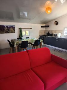 a living room with a red couch and a kitchen at Gîte Holidays mon repos in Saint-André
