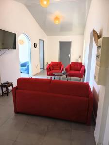 a living room with a red couch and two red chairs at Gîte Holidays mon repos in Saint-André