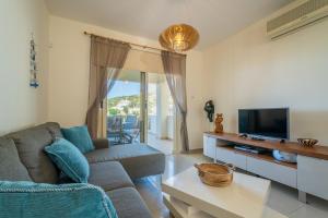a living room with a couch and a tv at Peyia Hilltop Retreat - Village Views & Sunsets in Peyia