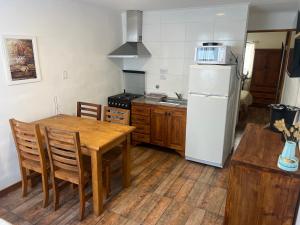 a kitchen with a wooden table and a white refrigerator at Mageeva Miramar Bs As Argentina Departamentos in Miramar