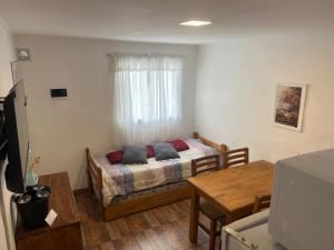a small room with a bed and a table at Mageeva Miramar Bs As Argentina Departamentos in Miramar