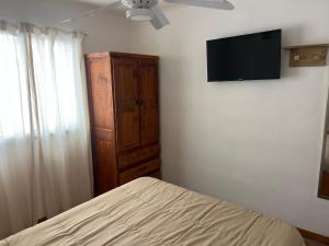 a bedroom with a bed and a tv on the wall at Mageeva Miramar Bs As Argentina Departamentos in Miramar
