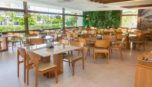 a restaurant with wooden tables and chairs and windows at Mana Beach Exclusive in Porto De Galinhas