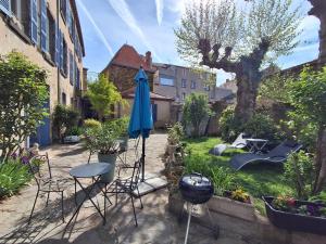 a patio with a table and a blue umbrella at Villa Toscane in Saint-Germain-Lembron