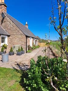 an external view of a stone house with a driveway at Broombarns Farm Cottage in Forgandenny
