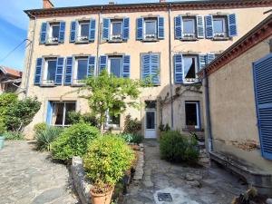 an old building with blue shuttered windows and plants at Villa Toscane in Saint-Germain-Lembron