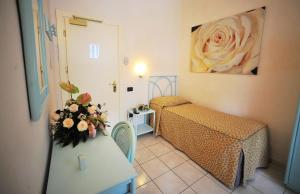 a small room with a bed and a table with flowers at Hotel Riviera Blu in Tirrenia