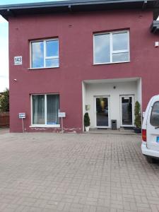 a red house with a car parked in front of it at Comfort Mile Apartments in Vilnius