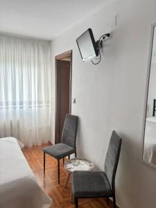 ein Schlafzimmer mit zwei Stühlen und einem Fernseher an der Wand in der Unterkunft Hostal Baviera in Pesués