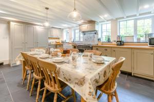 a kitchen with a long table with chairs and a kitchen with white cabinets at 4 Bed in Looe oc-p00795 in Lansallos