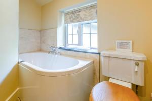 a bathroom with a tub and a toilet and a window at 4 Bed in Looe oc-p00795 in Lansallos +20 photos
