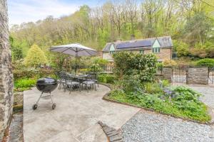 a backyard with a grill and a table with an umbrella at 4 Bed in Looe oc-p00795 in Lansallos