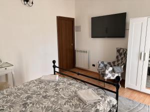 a bedroom with a bed and a chair and a flat screen tv at Novara Il Gallo in Lumellogno +3 photos