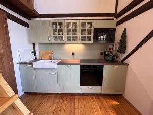 a small kitchen with white cabinets and a sink at Chalupa Pod Skalou Relax in Paseky nad Jizerou