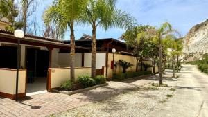 a house with palm trees next to a street at Eraclea Minoa Village in Montallegro