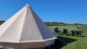 a white tent in a field with a table and chairs at Bell-tent Luna met uitzicht in Hensbroek
