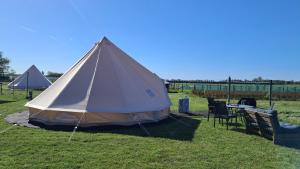 a tent in the grass with chairs and a table at Bell-tent Luna met uitzicht in Hensbroek