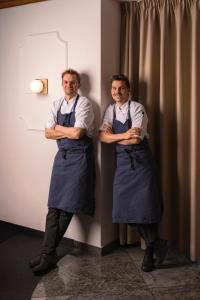 two men in aprons standing next to a wall with their arms crossed at Anett hotel in Vipiteno +202 photos