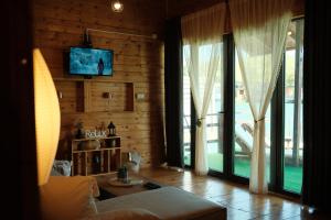 a living room with a couch and a tv and windows at Jack Sparrow's cottage- Ada Bojana River in Donji Štoj