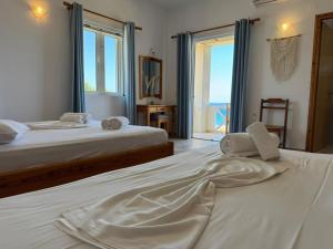 two beds in a bedroom with a view of the ocean at Kofini Falassarna in Falasarna