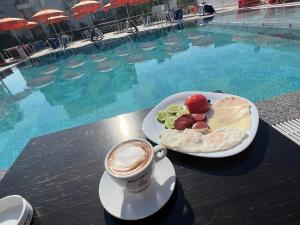 a plate of food and a drink in front of a swimming pool at Hotel BlueBalcony in Golem