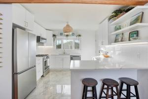 a kitchen with white cabinets and bar stools at Bright & Fully Renovated Retreat - Holiday Home in Saskatoon