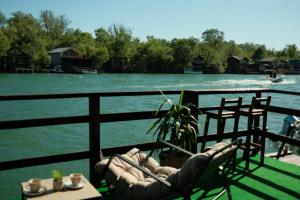 a balcony with chairs and a table and a body of water at Jack Sparrow's cottage- Ada Bojana River in Donji Štoj