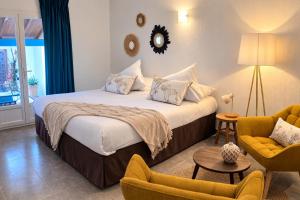a hotel room with a bed and two chairs at L'auberge Camarguaise in Saintes-Maries-de-la-Mer