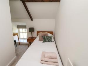 a bedroom with a bed with white walls at Snowdrop Cottage in Morpeth