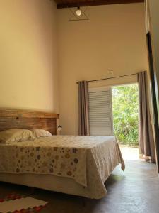 a bedroom with a bed and a large window at Morada do Ipê Pousada in Chapada dos Guimarães