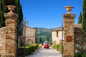 a red car driving down a street next to a gate at PODERE 1384 in Castellina in Chianti