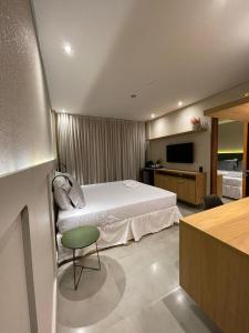 a bedroom with a bed and a desk and a television at Ap 101 concept BobZ in Barrinha