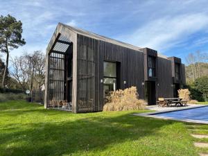 a black house with a pool in the yard at Villa Le Touquet, piscine privée, 4 chambres in Le Touquet-Paris-Plage