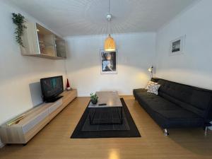 a living room with a black couch and a tv at Two room warm apartment Östavall in Östavall