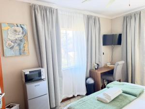 a bedroom with a bed and a desk and a window at Rugira Guest House in Vosburg