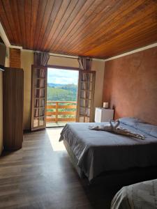 a bedroom with a large bed and a large window at Pousada AlpenRose in Campos do Jordão