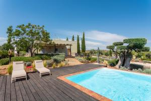 a swimming pool with two chairs and a house at Espargosa Monte de Baixo & Art in Castro Marim