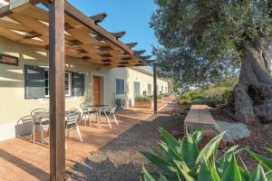 a patio with a table and chairs under a wooden pergola at Espargosa Monte de Baixo & Art in Castro Marim