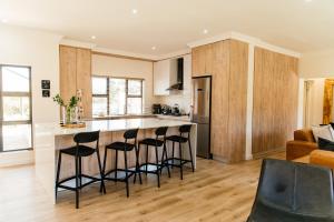 a kitchen with a bar with four stools at Pause Guesthouse in Clarens