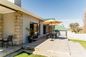 a patio with a table and an umbrella at Pause Guesthouse in Clarens