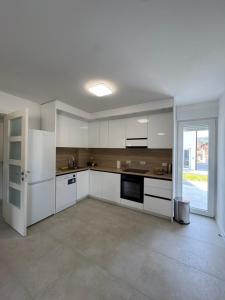 a kitchen with white cabinets and a large window at NMS Promet in Mrkonjić Grad