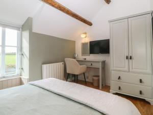 a bedroom with a bed and a desk and a tv at Seren Fach in Pwllheli