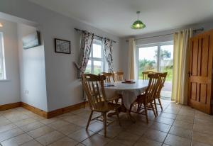 a dining room with a table and chairs and a window at Bray Head View 2 in Clynacartan