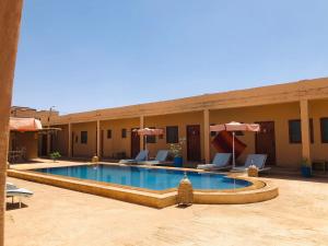a swimming pool in front of a hotel at Merzouga Hotel Activities in Merzouga