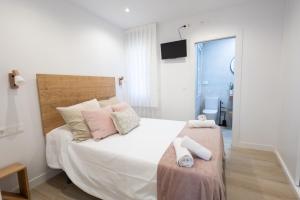 a bedroom with a large white bed with pink pillows at Apartamentos La Búsqueda in Cuenca
