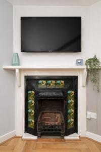 a fireplace with a flat screen tv above it at Lion Cottage - Dog-Friendly 3-Bed in Heart of Holt in Holt