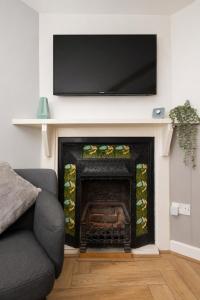 a living room with a fireplace with a flat screen tv above it at Lion Cottage - Dog-Friendly 3-Bed in Heart of Holt in Holt